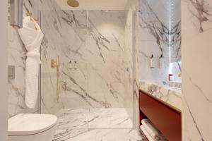 a white bathroom with a toilet and a shower at Mode Paris Aparthotel in Paris +30 photos