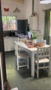 a kitchen with a white table and some chairs at Vientoafavorcabanas in Chascomús