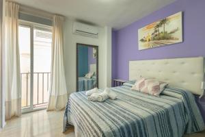 a bedroom with purple walls and a bed with two stuffed animals on it at Duque Center Premium Suites in Seville