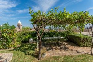 eine Terrasse mit einem Tisch und Stühlen unter einem Baum in der Unterkunft Le Contrade - Dimora nel Borgo in Santarcangelo di Romagna