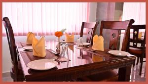a dining room table with chairs and a wooden table with yellow napkins at Hotel Royal Shivangi Palace - Near Holy Cross Hospital , Masuri Canal Bridge , mussoorie in Dāsna