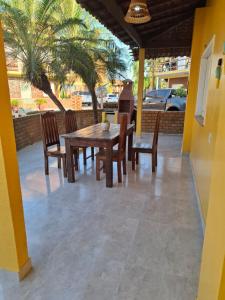 ein Holztisch und Stühle auf einer Terrasse mit Palmen in der Unterkunft Chalé Descanso - Cond Porto dos lençois Barreirinhas in Barreirinhas