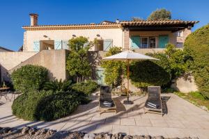 a patio with chairs and an umbrella in front of a house at Villa Miradou in Saint Paul de Vence