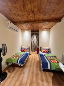 two beds in a room with a wooden ceiling at Hathors Terrace Apartment in Luxor