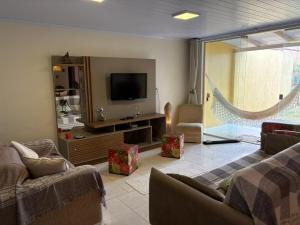 ein Wohnzimmer mit Sofa und Fernseher in der Unterkunft Casa Piccolo Paradiso 4 quartos in Balneário Gaivotas