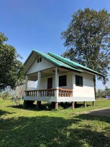 ein kleines weißes Haus mit einer Veranda auf einem Feld in der Unterkunft ฟาร์มผัก Thank you in Ban Kom