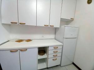 Una cocina con gabinetes blancos y un refrigerador blanco. en Residence Due Torri Tipo C, en Lignano Sabbiadoro
