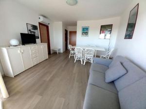 Una sala de estar con un sofá, una mesa y sillas. en Residence Due Torri Tipo C, en Lignano Sabbiadoro
