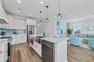 a large kitchen with white cabinets and a living room at Bright Waves Fort Morgan in Gulf Shores