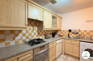 a kitchen with a sink and a stove top oven at Central Woking 2 Bedroom 2 Bath Modern Apartment with Parking in Woking