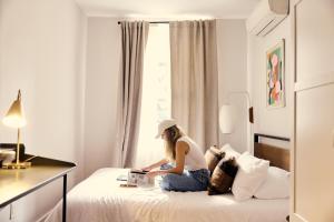 a woman sitting on a bed reading a book at Outsite Chelsea in New York