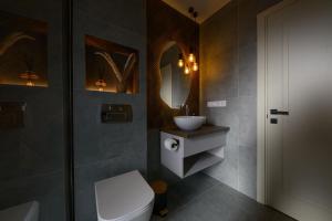 łazienka z toaletą, umywalką i lustrem w obiekcie Domivka котедж із чаном-джакузі, каміном і кіно-зоною у Cлавську w Sławsku +56 zdjęć