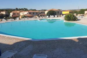 Vignola MareAffittaSardegna - Domo Vignola的一座带椅子和建筑的大型蓝色游泳池