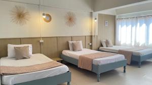 una habitación con dos camas y una ventana en A Day Rayong, en Ban Pa Khan