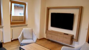 a living room with a flat screen tv and a chair at Kurapotheke in Bad Hofgastein +1 photo