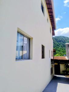 a white building with a window and mountains in the background at Espaço inteiro-Praia de Barequeçaba - São Sebastião -SP in São Sebastião +20 photos