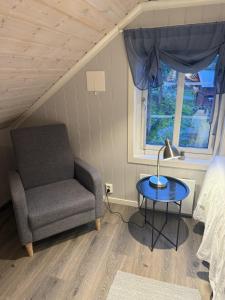 a bedroom with a chair and a table and a window at Rosenli Gård in Tønsberg