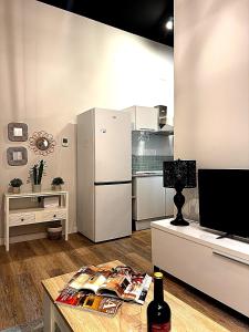 a kitchen with a refrigerator and a table with a bottle of wine at Apartmento Ópalo in Seville