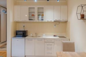 a kitchen with white cabinets and a sink and a microwave at GALAKTIK centar in Apatin