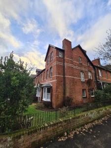 um velho edifício de tijolos com uma cerca em frente em The Shrubbery-Superb Modern home-6 beds-sleeps 11 em Topsham