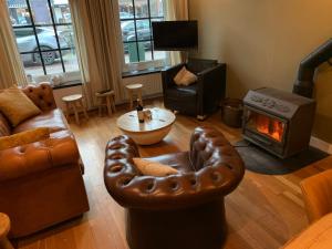 a living room with leather furniture and a fireplace at Herenhuis aan het water in centrum Sluis in Sluis