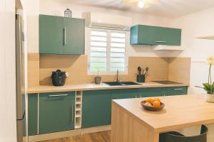 a kitchen with green cabinets and a table with a bowl of fruit at La Grippiere in Petit-Bourg