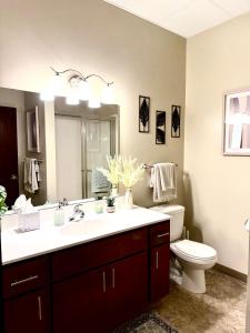 Un baño con lavabo, inodoro y espejo. en The Luxe Loft Boho Chic, en Duluth