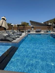 a large swimming pool with chairs and an umbrella at Veray Homes Villa in Ayios Dhometios