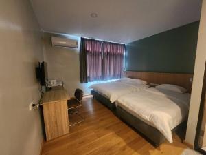 ein Hotelzimmer mit zwei Betten und einem Fernseher in der Unterkunft Wan Residence Ratchatewi in Bangkok