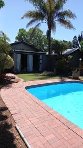 a swimming pool with a brick walkway next to a house at Garden View Inn in Cape Town