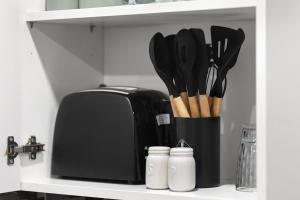 a kitchen shelf with a container of knives and a toaster at Convenient Studio and Parking Easy Access Cntr London in Perivale