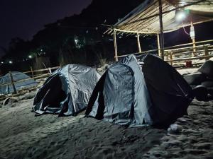 two tents in the sand on the beach at night at Rickson Riverside Campsite in Dawki