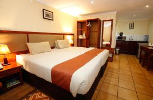 a hotel room with a large bed and a kitchen at Mokoro Lodge in Maun