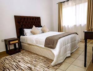 Metris Foxdale Apartments في لوساكا: غرفة نوم بسرير كبير ونافذة