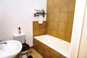 un bagno con vasca, WC e lavandino di Metris Foxdale Apartments a Lusaka Altre 2 foto