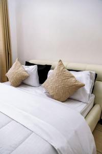 Metris Foxdale Apartments في لوساكا: سرير عليه ملاءات ووسائد بيضاء