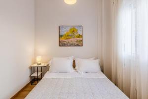 a white bedroom with a bed with white pillows at Monemvasia modern flat nearby sea in Monemvasia