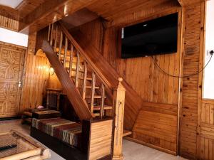 a living room with a wooden staircase with a flat screen tv at Naini Lake View The- Gwen -Stays Mall Road - Lake View Rooms Types- Prime Location - Best Luxuary Hotel In Nainital in Nainital