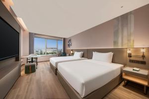 a hotel room with two beds and a flat screen tv at Holiday Inn Yiwu Center by IHG in Yiwu +39 photos