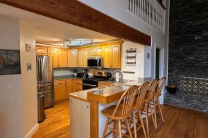 a kitchen with wooden cabinets and a counter with chairs at Middle Pines Chalet in Warren