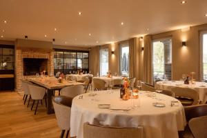 a restaurant with white tables and chairs and a fireplace at Ferme d'Ecavée in Celles