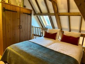 una camera da letto con un letto con lenzuola bianche e cuscini rossi di Erfgoed & Logies Den Heijkant a Moergestel