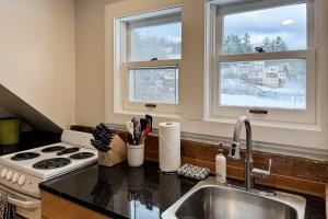 Una cocina con fregadero y estufa y dos ventanas. en Stowe Mountain Road Retreat, en Stowe 19 fotos más
