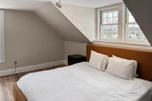 1 dormitorio con 1 cama con sábanas blancas y 2 ventanas en Stowe Mountain Road Retreat, en Stowe