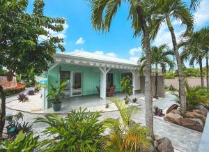a green house with palm trees in front of it at Ti Verger in Sainte-Luce