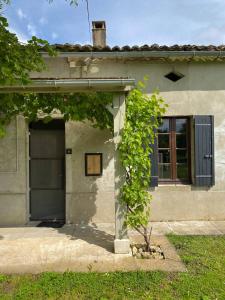 un edificio con una puerta y un árbol delante de él en Le Petit Four à Pain - Maison 4 personnes à la Campagne, en Neuvicq-Montguyon