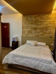 a bedroom with a large bed with a brick wall at Kubu alit guest house Seminyak in Seminyak