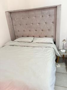 a bedroom with a large white bed with a padded headboard at Hlones place in Rustenburg