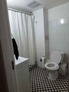 a bathroom with a toilet and a black and white tile floor at GuestHouse Habitaciones SANTIAGO CENTRO in Santiago