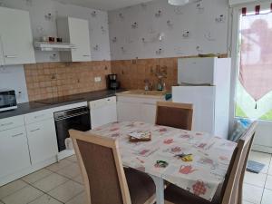 una cucina con tavolo e sedie e una cucina con elettrodomestici bianchi di Chez Monique 